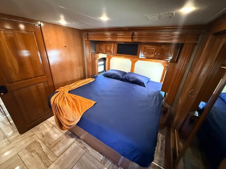 Comfortable RV bedroom with wooden cabinets and blue bedding.