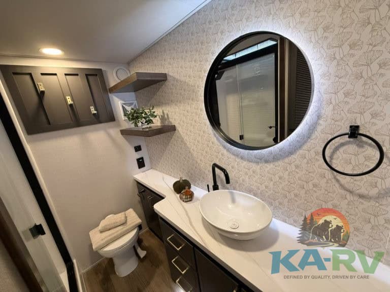 Contemporary RV bathroom with round mirror, vessel sink, and stylish decor.