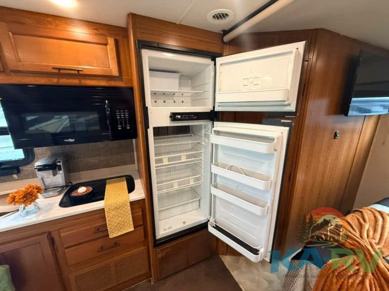 RV refrigerator with open doors showing empty interior.