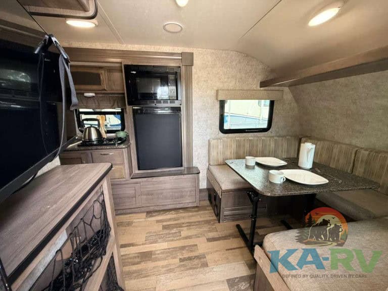 RV interior with kitchen and dining area in a 2017 Winnebago Winnie Drop 1780.