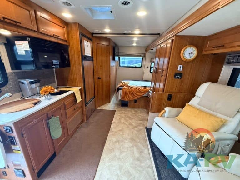 Cozy RV interior with kitchen, seating, and sleeping area.