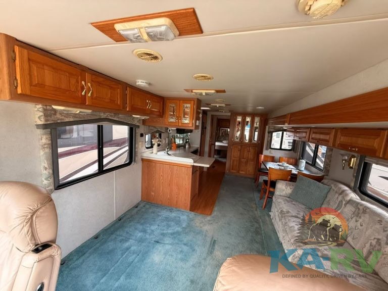 RV interior with wooden cabinetry, sofa, and dining area in a well-maintained camper at KA RV Repair.