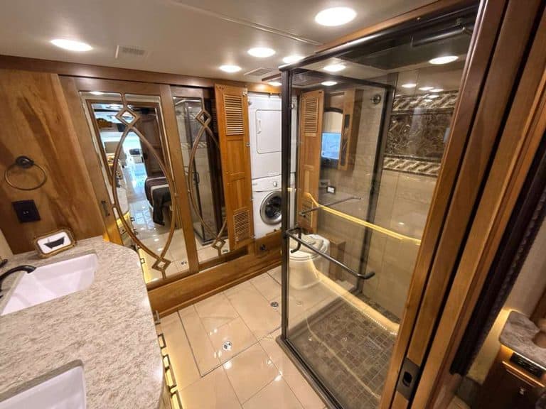 Luxury RV bathroom with shower, sink, and wooden cabinets.