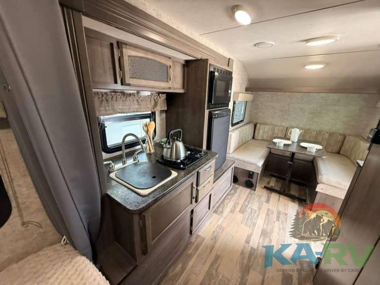 Interior view of a 2017 Winnebago Winnie Drop RV kitchen and dining area.