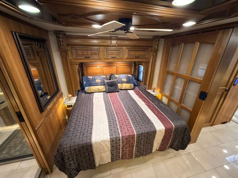 Luxury RV bedroom with wooden cabinetry and king-sized bed.