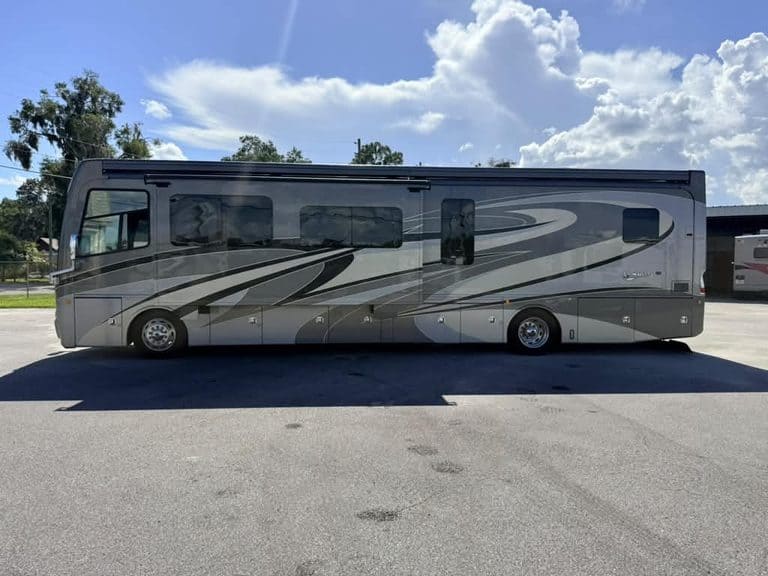 Luxury Class A RV parked outdoors with scenic sky background.