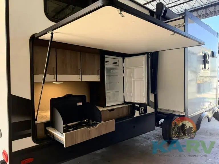 Modern RV kitchen slide-out with refrigerator and cooking space for optimal travel convenience.