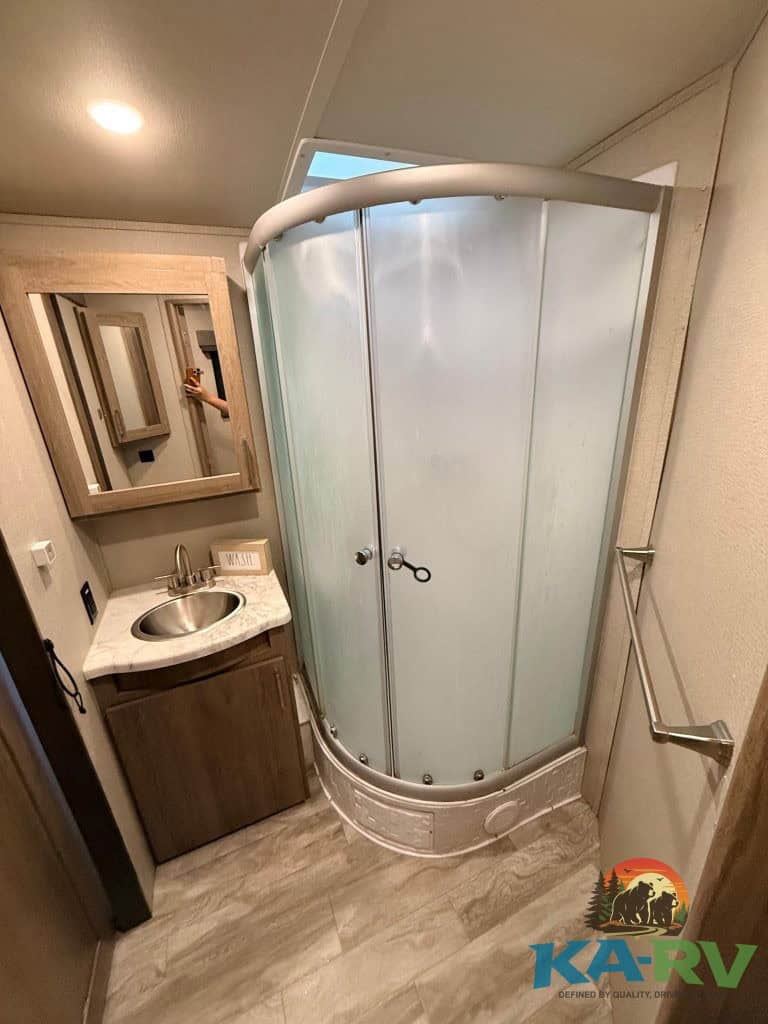 RV bathroom shower with frosted glass doors and compact vanity for optimal space.