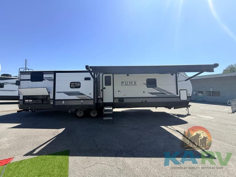 RV repair technician working on a Puma RV trailer in a service lot.