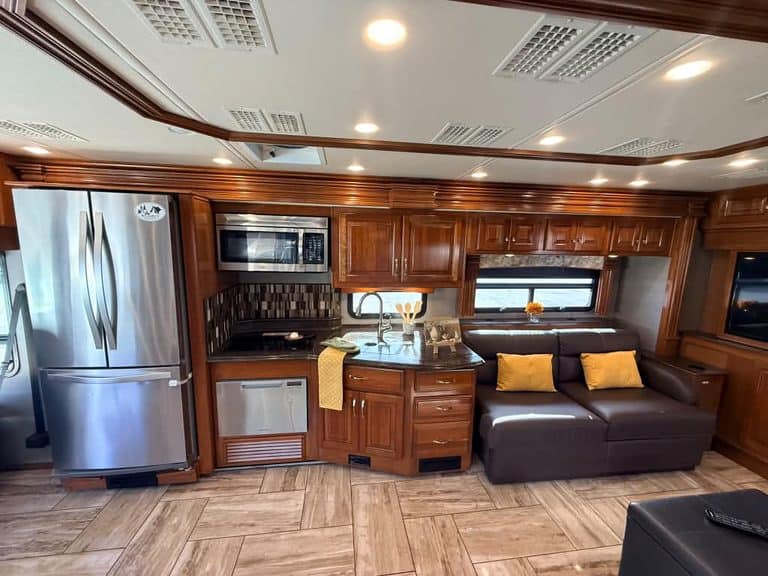 Modern RV interior with kitchen, sofa, and wooden cabinets for travel comfort.