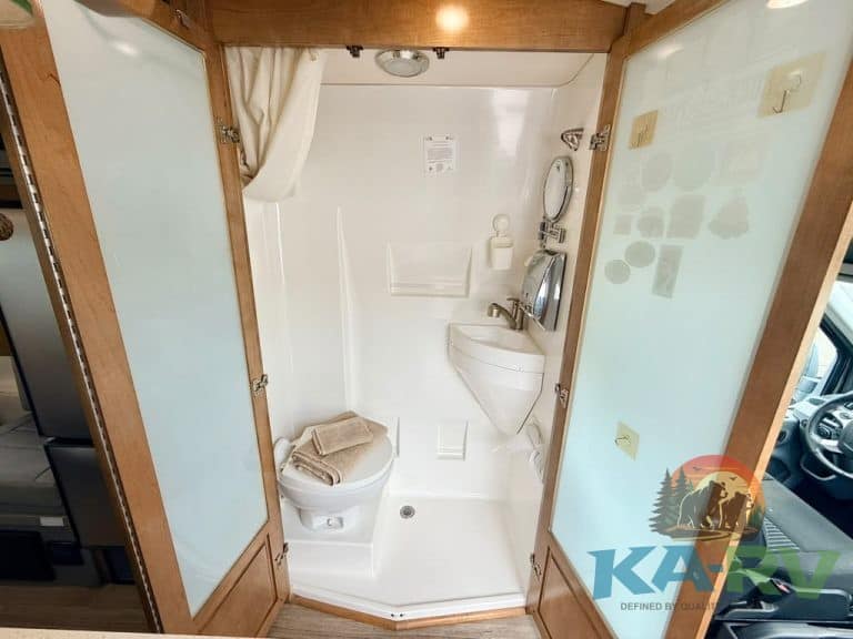 Small RV bathroom with shower, toilet, and sink in a compact space.