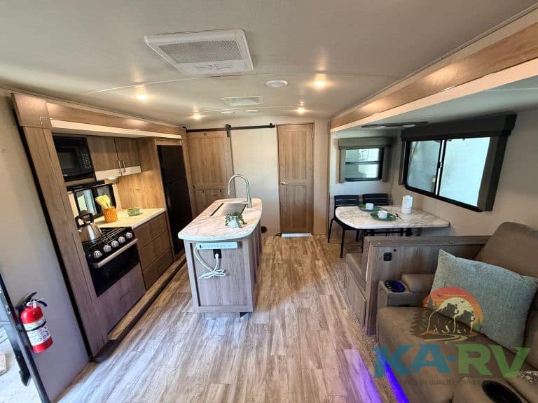 Kitchen and living space inside a camper van with modern appliances and cozy seating.