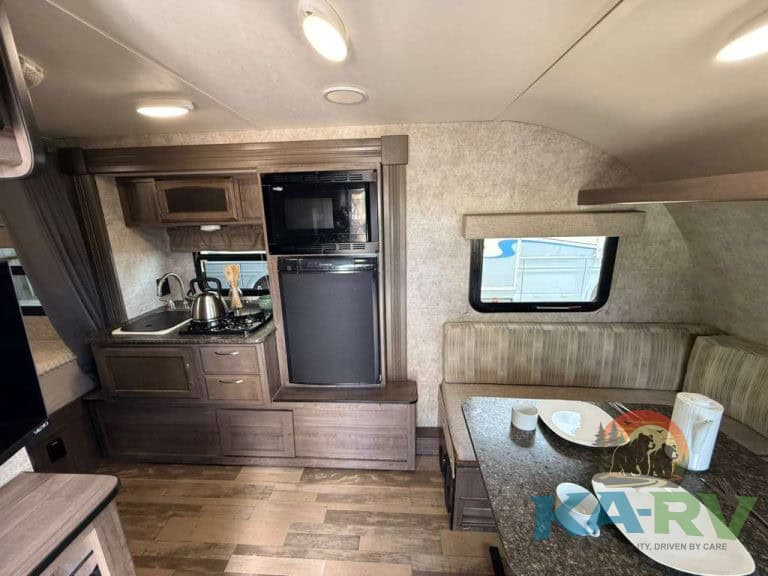RV interior with kitchen and dining area in a 2017 Winnebago Winnie Drop 1780.