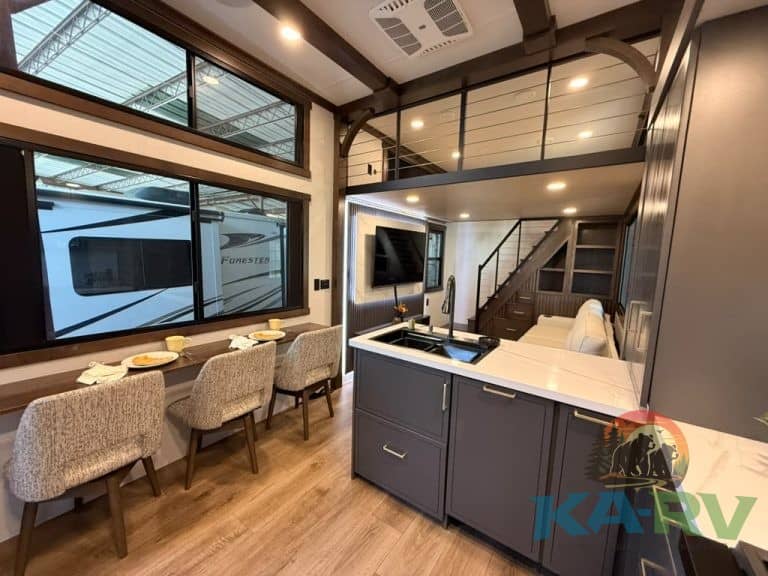 Interior of a modern RV with kitchen, dining area, and loft space.