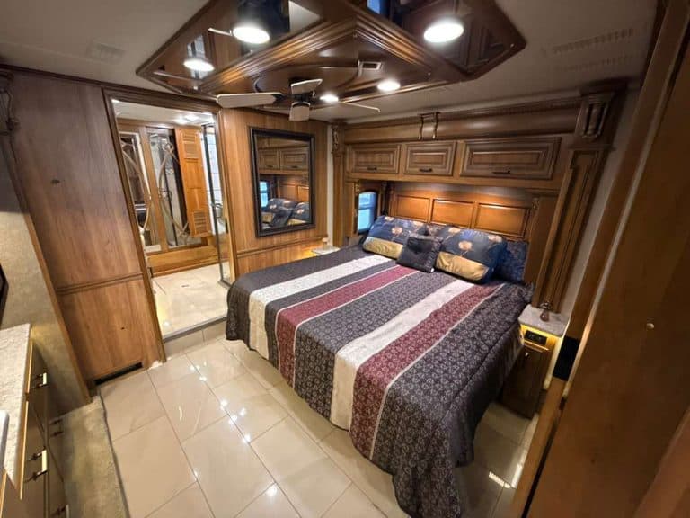 Luxury RV bedroom with wooden cabinetry and king-sized bed.