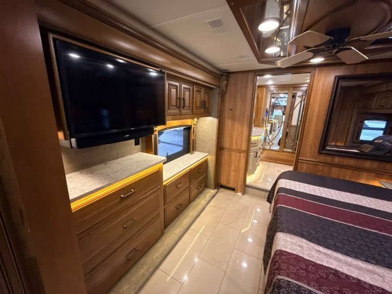 Interior view of a 2016 Entegra Cornerstone 45B RV with wooden cabinets and a large TV.