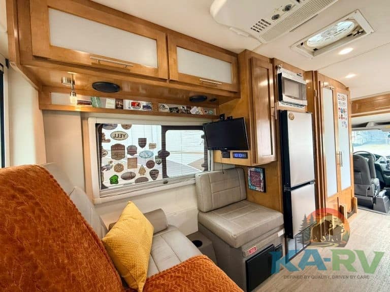 Cozy RV interior with sofa, kitchen, and storage cabinets for travel comfort.
