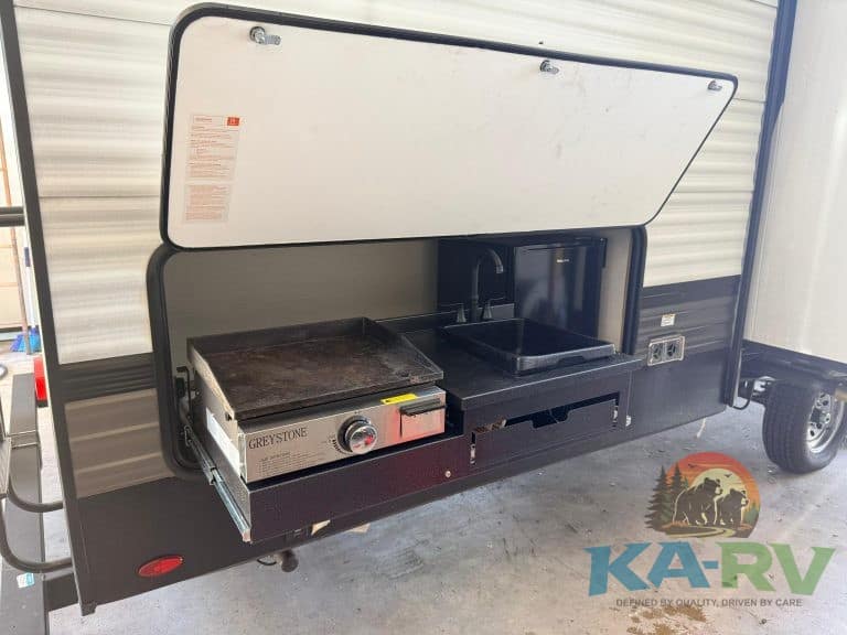 Outdoor RV kitchen slide-out with cooking stove and storage compartments for optimal camping conveni.