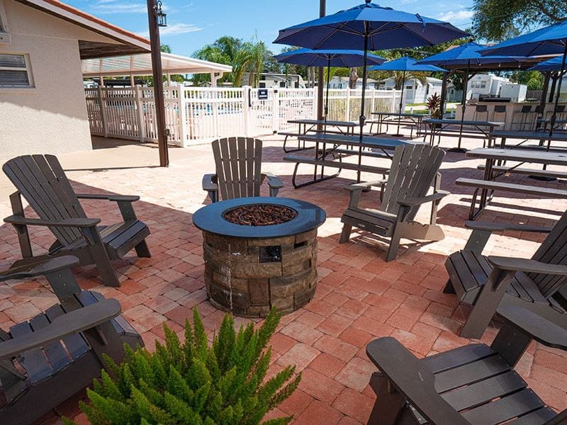 Cozy outdoor fire pit area at Daytona Beach RV park with seating and umbrellas.