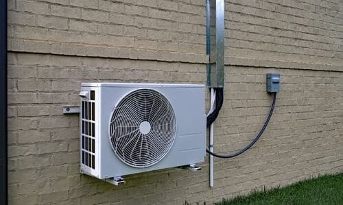 Outdoor ductless mini split air conditioning unit on building wall.