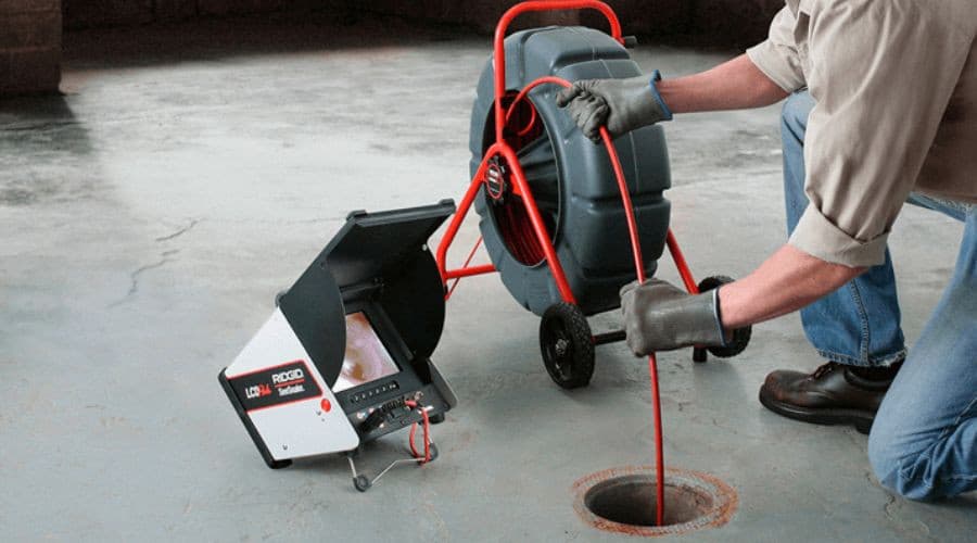 Technician using drain inspection camera for plumbing maintenance.