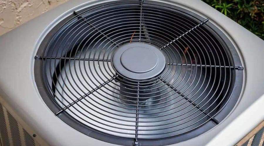 Close-up of a round HVAC air conditioner fan with protective grille.