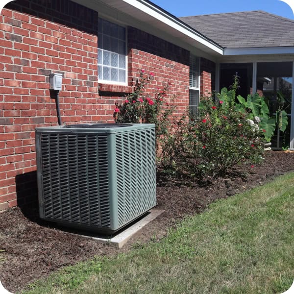 HVAC air conditioning unit outside a brick house with garden and window.