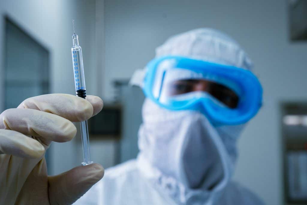 isolated injection syringe close up. person holding a pre filled syringe. injection syringe in hand. manufacturing of PFS syringes. syringe injection for cardiology. Pharmaceutical production line.