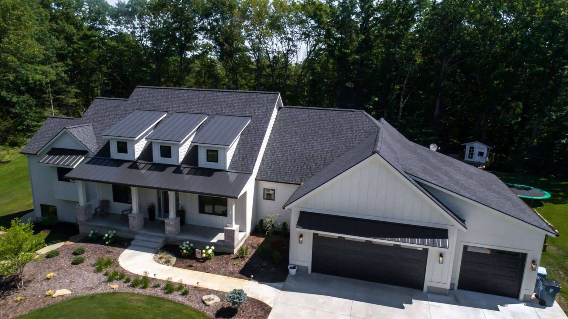 New Livingston Homes featuring a large garage and modern design in a green, wooded area.