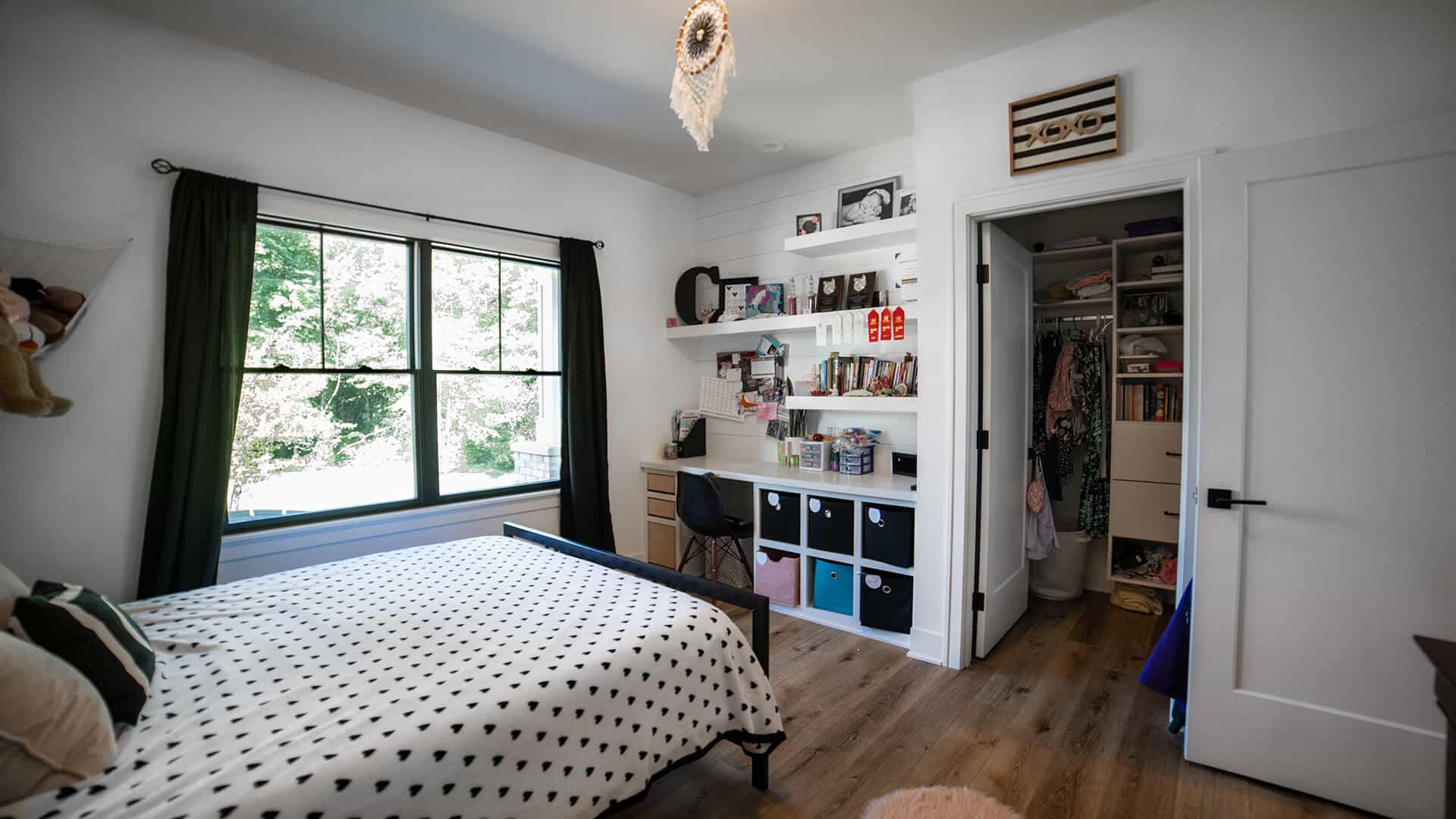 Bright bedroom featuring a large window, stylish decor, and an organized walk-in closet.