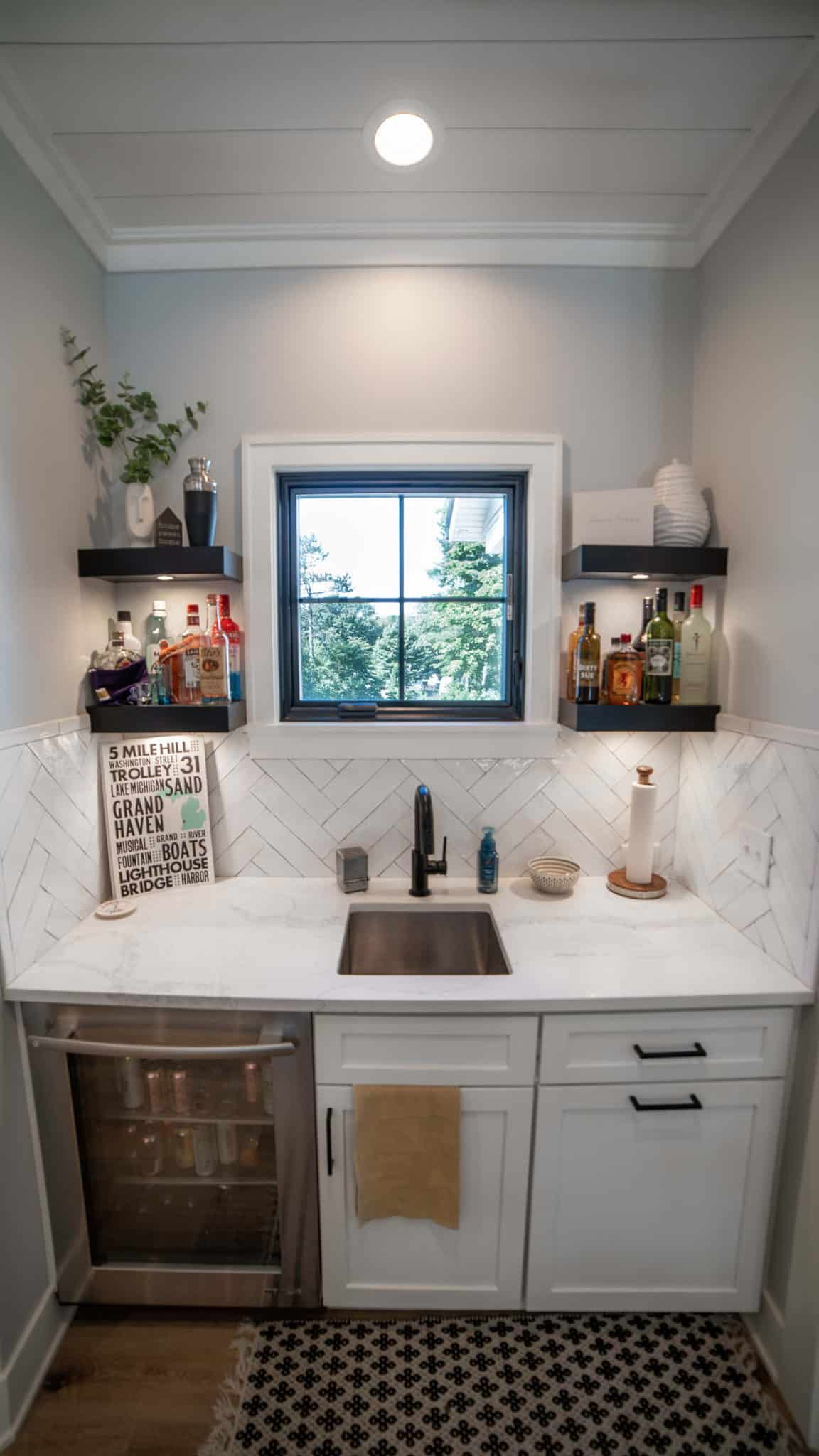 Bright kitchen featuring white cabinets, marble backsplash, and a central window.