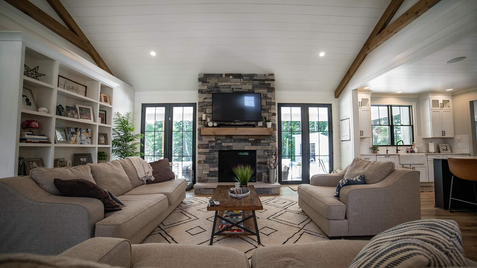 Spacious living room with modern decor, stone fireplace, and large windows in Livingston Homes.