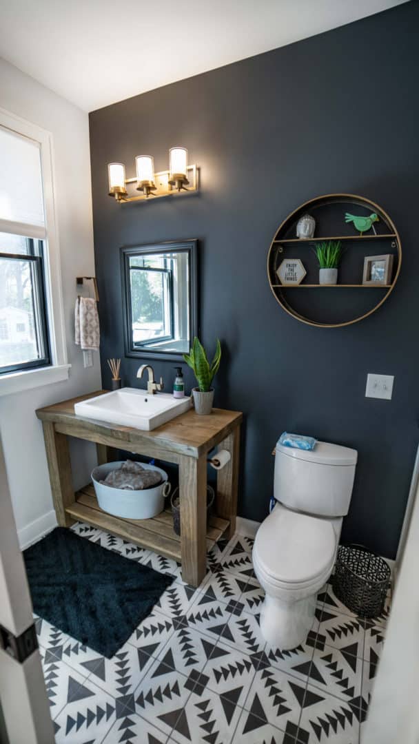 Bathroom with contemporary design featuring a dark accent wall, modern lighting, and decorative shel.