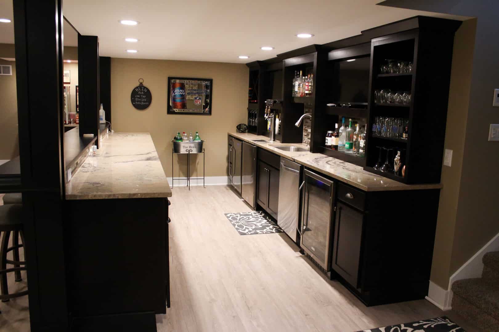 Modern home bar with black cabinetry and glassware display.