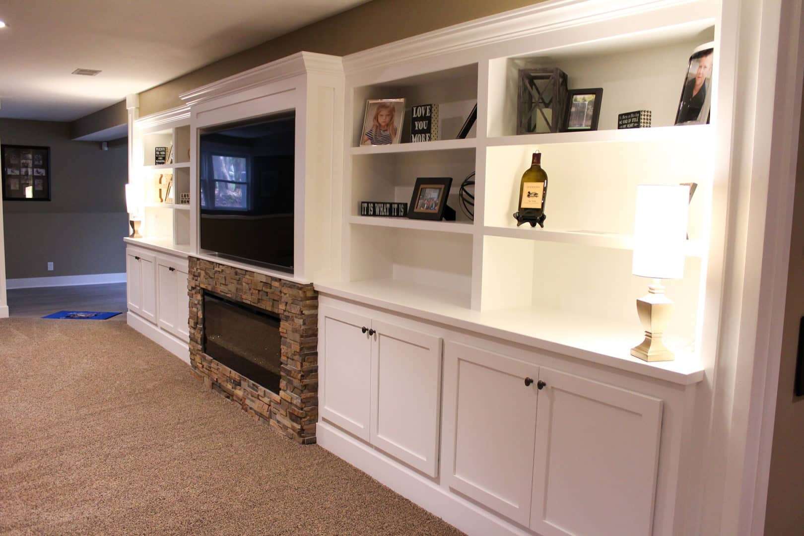 Custom built-in white shelves with fireplace and decor in living room.