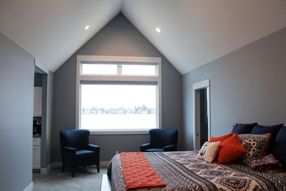Modern bedroom with vaulted ceiling and large window in Livingston Homes.