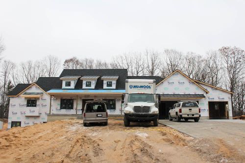 New residential home under construction with trucks and building materials.