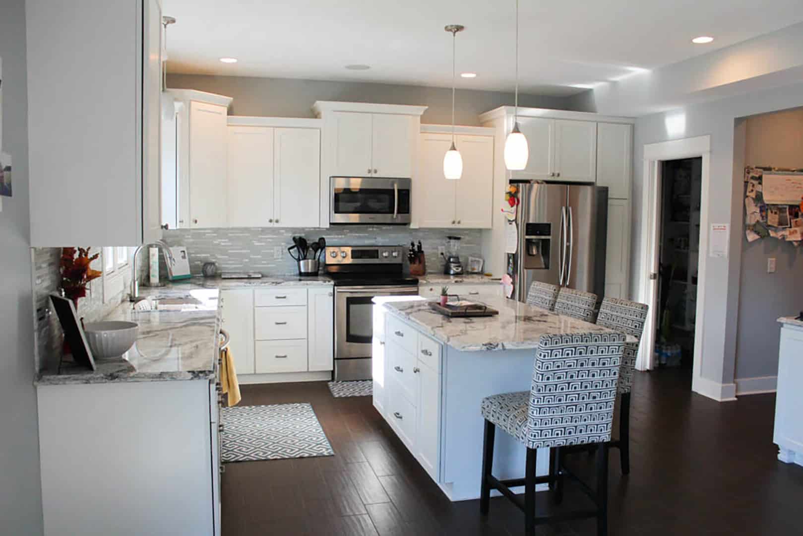 Bright, spacious kitchen featuring white cabinetry, a central island, and stainless steel stove and.
