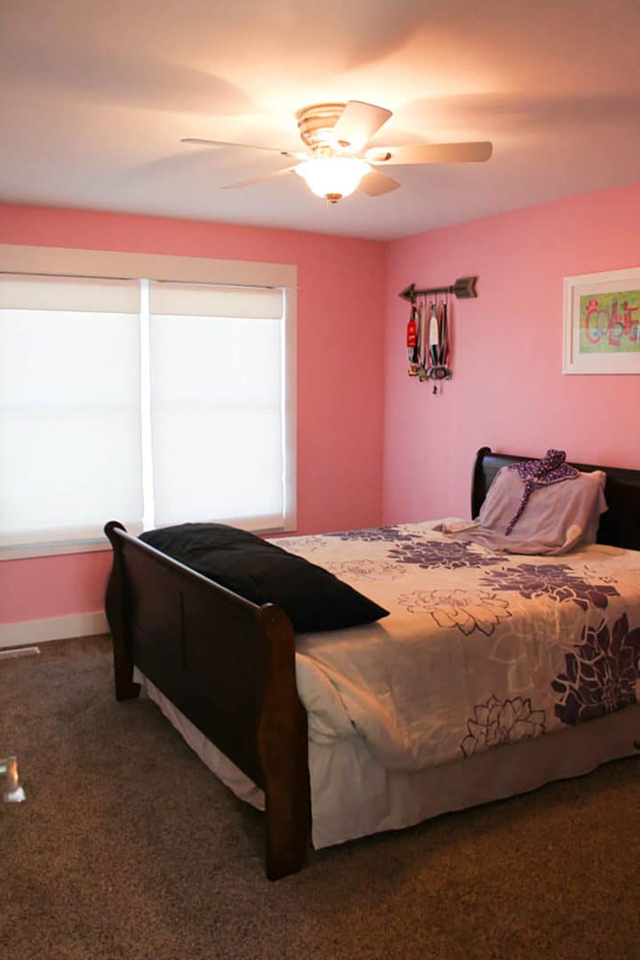 Livingston Homes bedroom with pink walls, large window, and cozy bed setup.