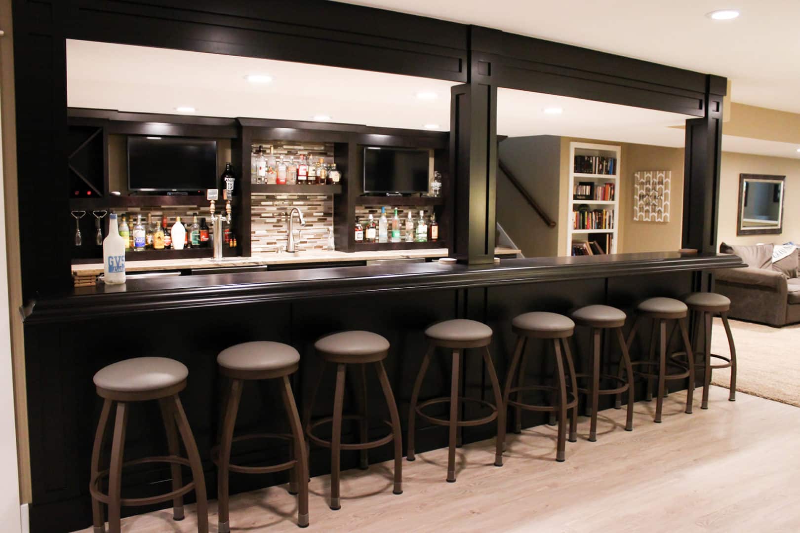 Modern home bar with seating and entertainment area by Livingston Homes.