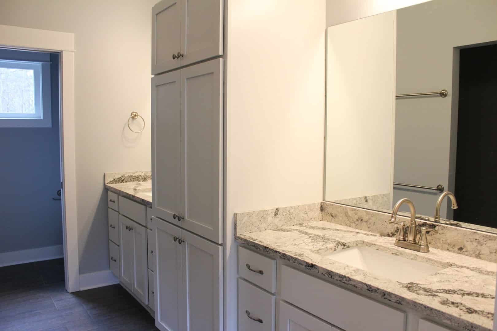 Modern bathroom vanity with granite countertop and white cabinetry.