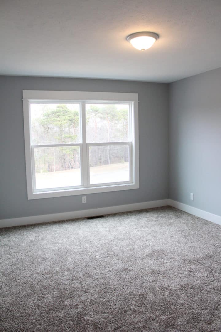 Living room featuring a spacious area with a big window and neutral gray walls. Perfect for relaxing.