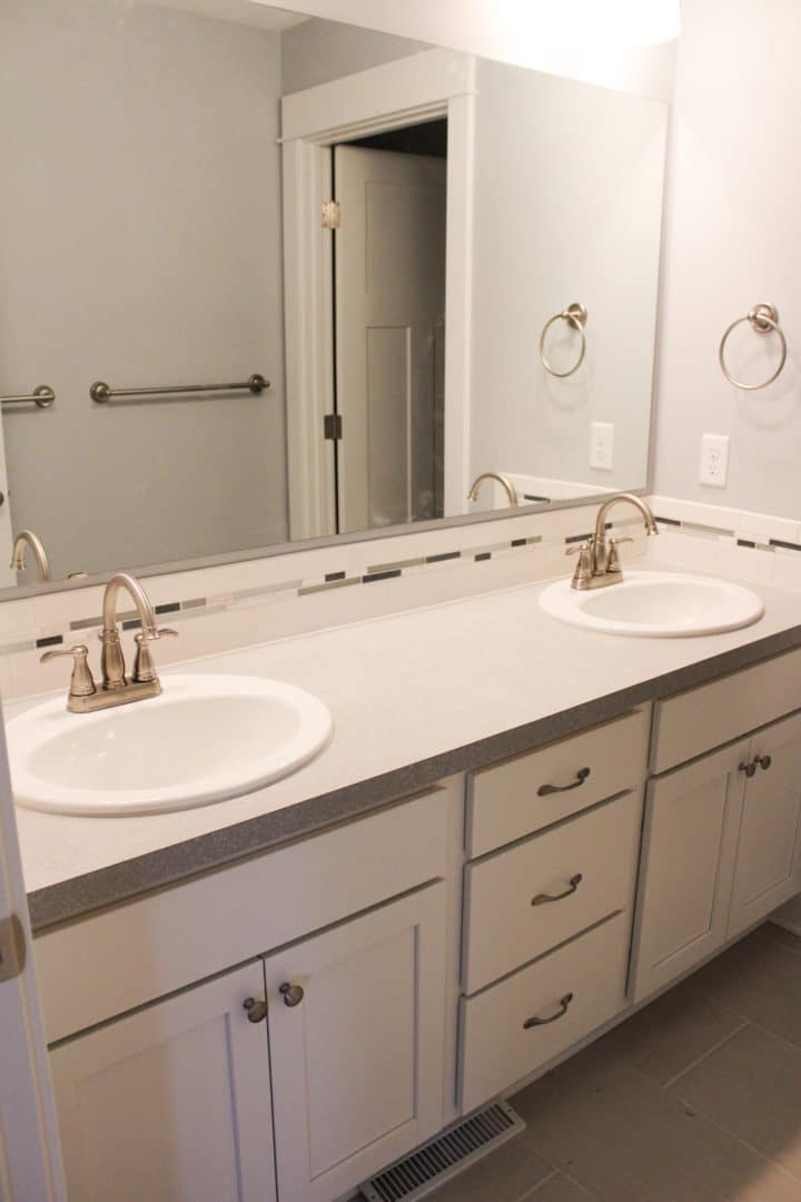 Double vanity bathroom with white cabinets, granite countertop, and modern fixtures.