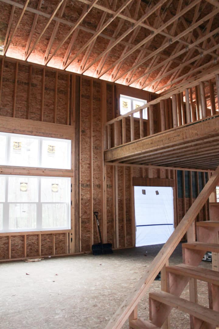 Interior view of a new home under construction with exposed wooden framing and unfinished walls.
