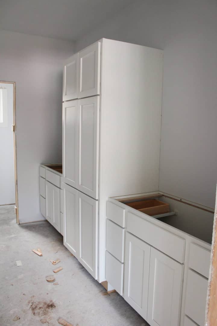 White kitchen cabinets with tall upper and lower storage units for modern home design.