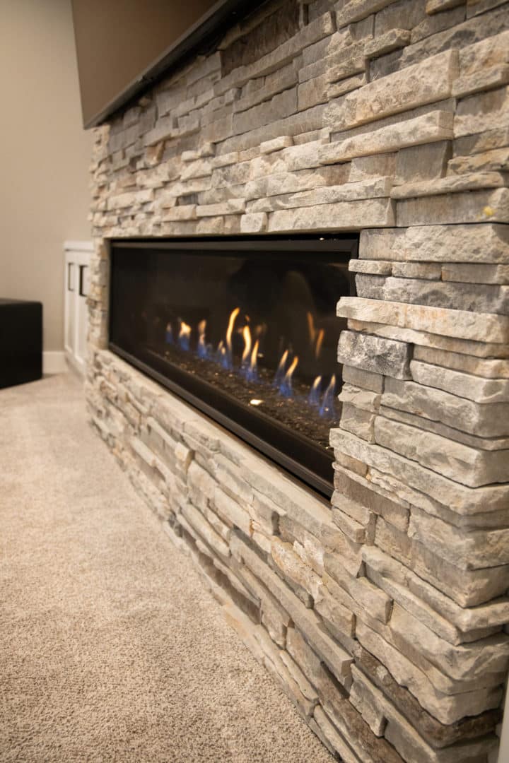 Elegant stone fireplace with gas flames in a contemporary living space.