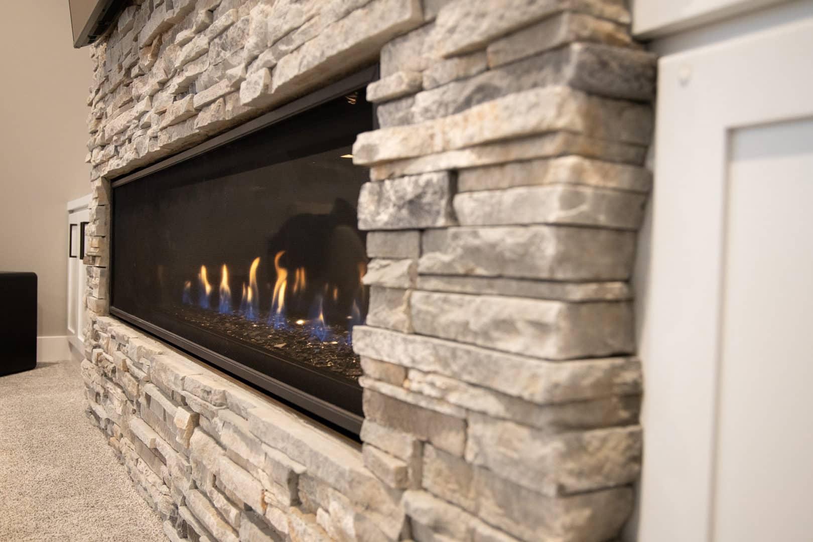 Elegant gas fireplace with stacked stone surround.