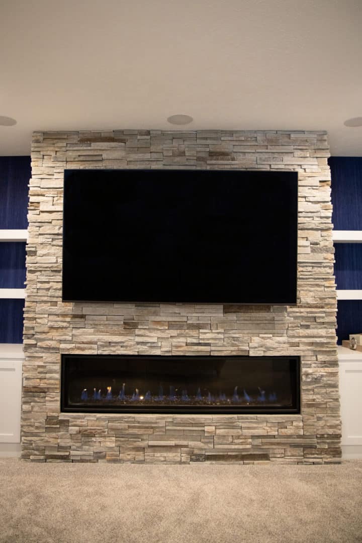 Living room fireplace with mounted TV and stone accent wall for modern home design.