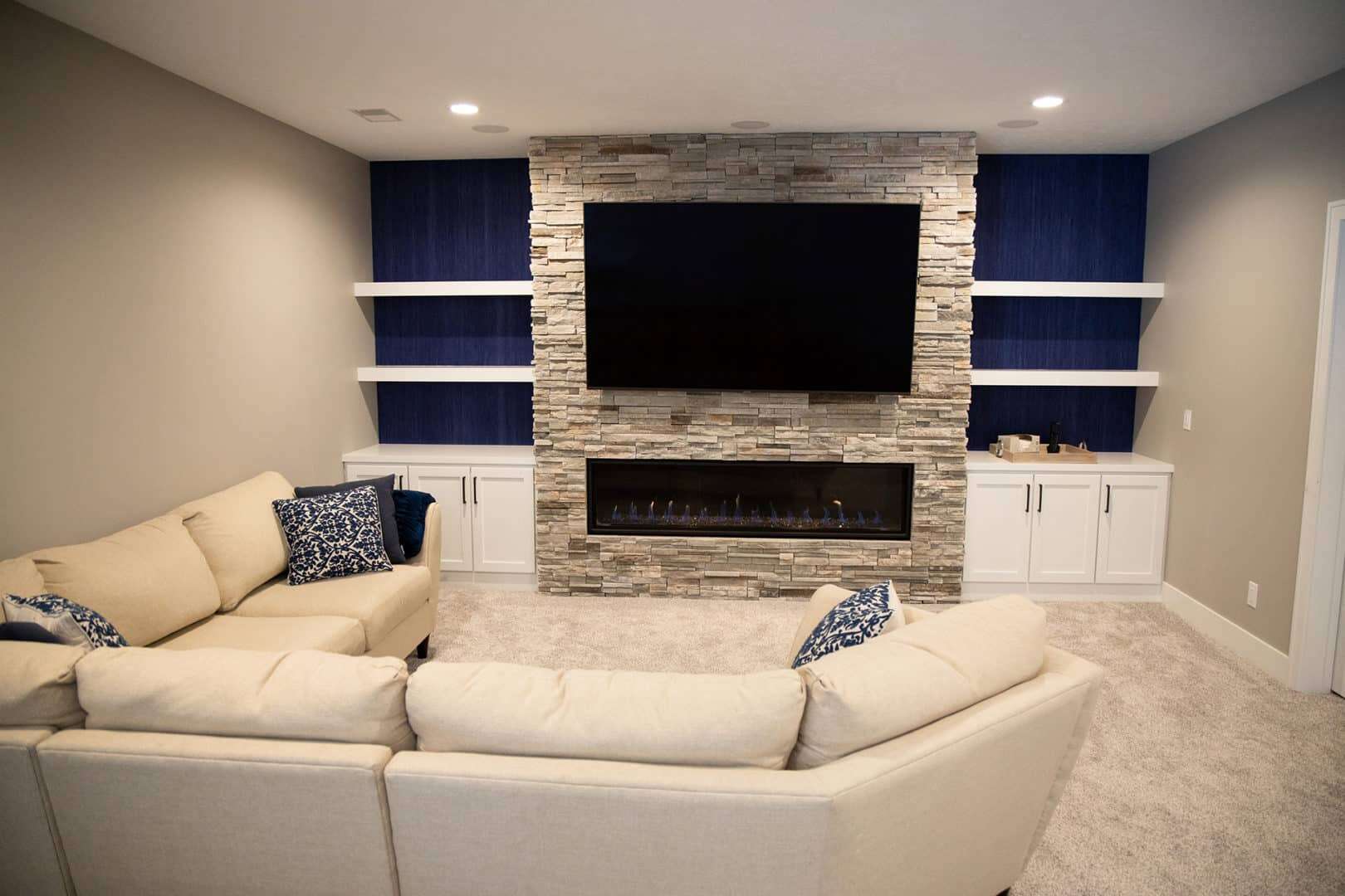 Living room with stone fireplace, wall-mounted TV, and built-in white shelves for a cozy, stylish sp.