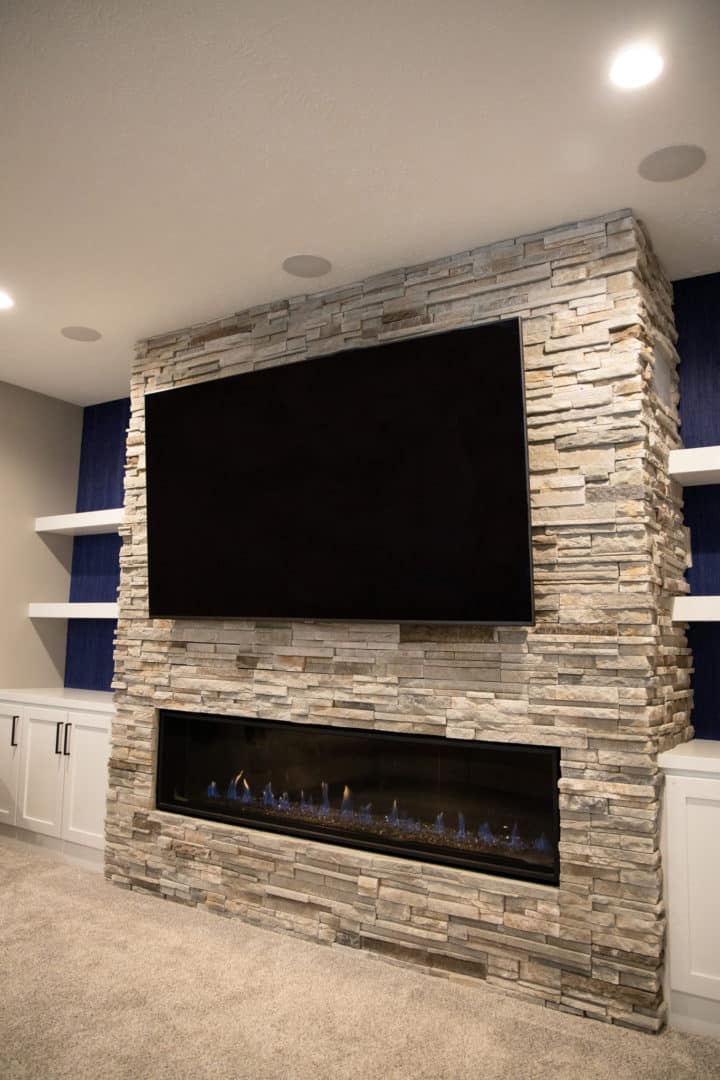 Living room with stone fireplace and mounted flat-screen TV.
